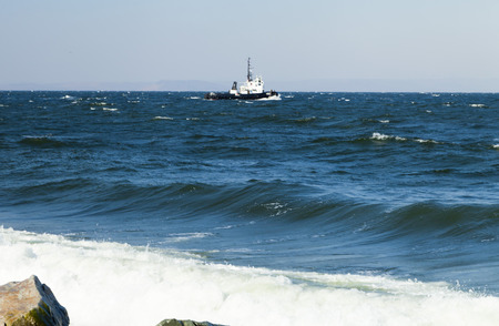 Small ship in the sea rocks in the big waves