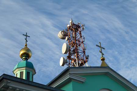 Communication tower against the bright blue sky with cloudsの写真素材