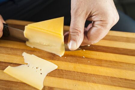 The piece of cheese on a table prepares for giving and therefore he is cutの写真素材