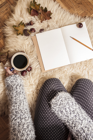 Relaxing autumn day at home with coffee and blank notebook for copyspace in warm coziness scandinavian hygge styleの写真素材