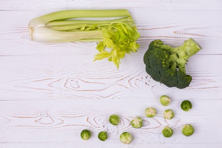Top view of fresh broccoli, Brussels sprouts and celery on a white wooden table. Vegetarian concept. Place for text.の写真素材