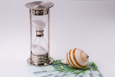 EURO banknotes, hourglass and seashell on white background. Concept - time to travel.の写真素材