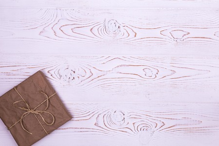 Gift or present box wrapped in kraft paper on white wooden background from above. Rustic flat lay styling. Copy space for text.の写真素材