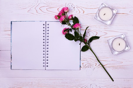 Blank notebook, flower, candles on a white background from above. Flat styling. Copy space for text.
