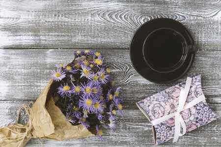 Cup of coffee, present box and flower wrapped in kraft paper on gray table from . Flat lay styling. Copy space for textの写真素材