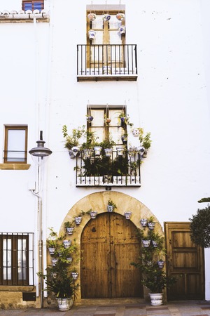 Facade of old European house with windows, balcony with flowers, wooden door in the shape of an arch.の写真素材
