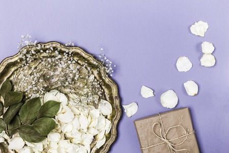 Dry petals of white roses and gypsophila on a beautiful antique tray, a gift wrapped in craft paper...