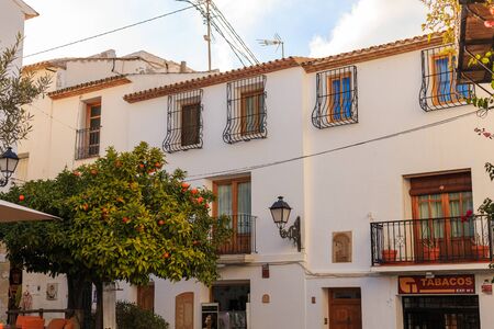 Altea, Spain - 19 February 2019: View of a white house with a tiled roof and balconies and a forged...
