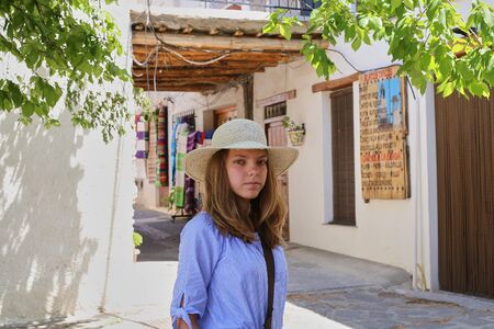 Capileira, Andalusia, Spain - May 29, 2019: Beautiful Caucasian European girl in a straw hat walking along the narrow streets of the old city.のeditorial素材