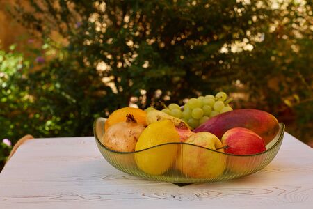 Juicy fruits on a plate on a table on the terraceの写真素材