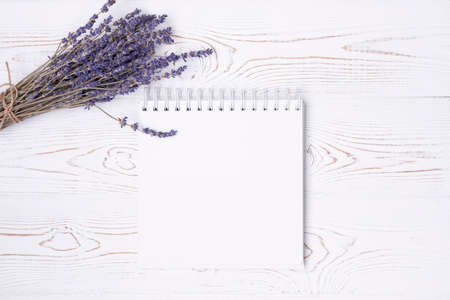 Composition from blank diary, cup of coffee and macaroon and lavender flowers on a white shabby wooden table. Fashion flat lay.の写真素材