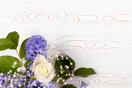 Top view of blue hyacinth flowers and white roses on a white wooden table with space for text....