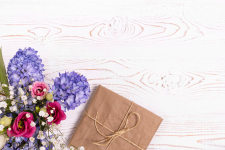 Top view of the gift box wrapped in kraft paper and blue hyacinth flowers, pink flowers on the white table top. Copy space for textの写真素材