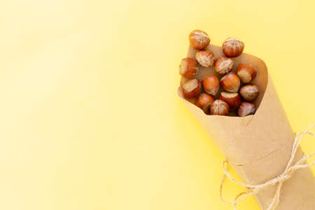 Hazelnuts screw on a yellow background. Nuts wrapped in eco kraft paper and twine, flat lay, copy space.の写真素材