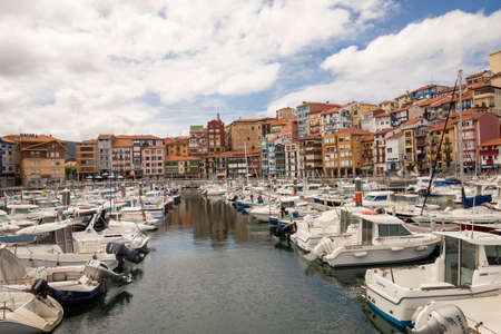 Bermeo, Basque Country, Spain - July 16, 2020: fishing port with colorful facades of houses and fishing boats against the backdrop of a beautiful cloudy sky.のeditorial素材