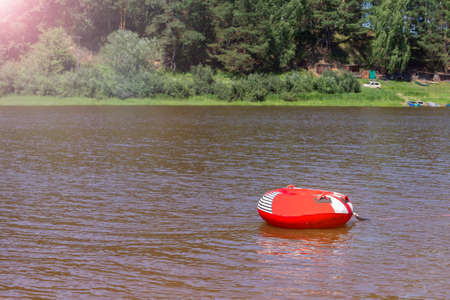 Floating ring of red color on the water in the river on a summer sunny dayの写真素材