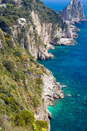 View of the coastline of the island of Capri, Italy, with one of its seaside rock formations known as the Faraglioni, vertical photo.の写真素材