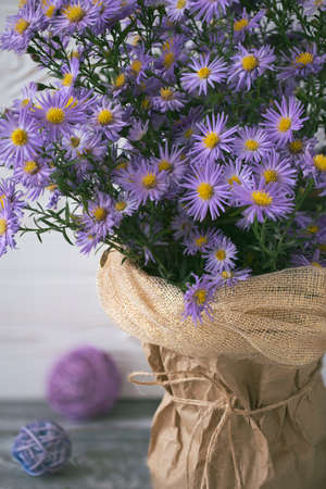 Autumn composition with lilac flowers in a vase and rattan balls on a table.の写真素材