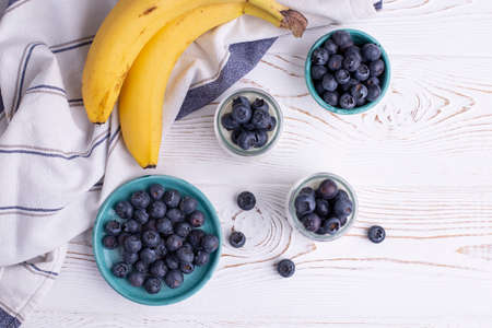 Organic blueberries and bananas at a rustic whitewashed table. Healthy eating conceptの写真素材
