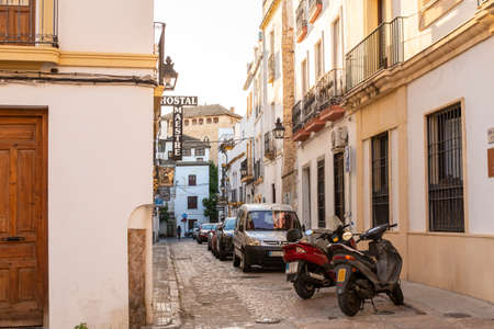 Cordoba, Andalusia, Spain - November 5, 2021: View of a narrow residential cobblestone street, facades of houses with balconies, as well as signs of hotels and cafes, cars and motorcycles parked in the Old Town.のeditorial素材