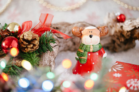 Close-up Christmas holiday background with a ceramic elk dressed as Santa Claus among the Christmas tree with cones, balls, bokeh, copy spaceの写真素材