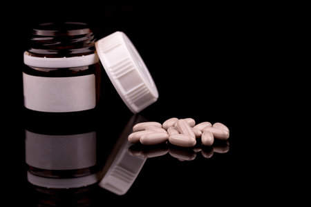 Medical concept of prescription pills and bottle on black background, with reflection, copy spaceの写真素材