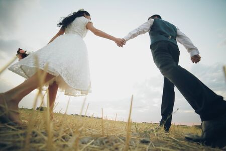 Wedding. Bride and groom hold hands and meet the sunset. A beautiful couple. High quality photoの写真素材