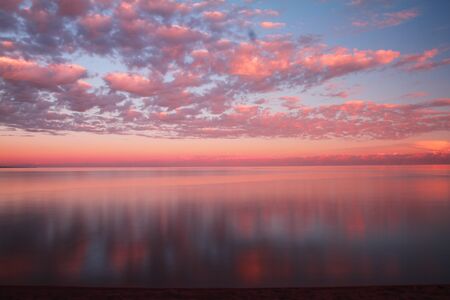 Clouds reflected on the water during sunset. High quality photo.の写真素材