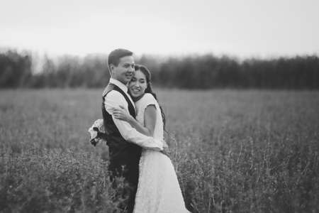 The bride and groom hold hands, hug each other and walk in the park. wedding. High quality photoの写真素材