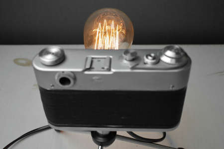 Retro lamp from an old camera with an Edison lamp on a gray background. Concept is a good idea. High quality photoの写真素材