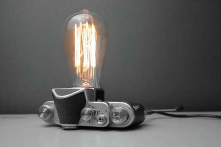 Retro lamp from an old camera with an Edison lamp on a gray background. Concept is a good idea. High quality photoの写真素材