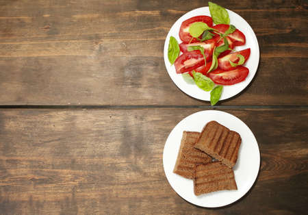 Sliced tomatoes with lettuce on a white plate. Fresh bread toast. Healthy eating concept. High...