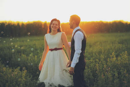 Wedding. The bride and groom hold hands and walk in the park in the sunset lightの写真素材