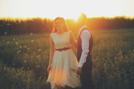 Wedding. The bride and groom hold hands and walk in the park in the sunset lightの写真素材