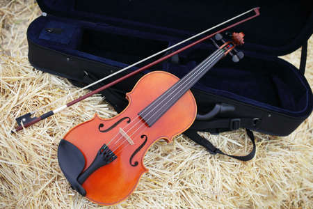 One violin and bow placed on a pile of straw in the field. Music Violin training. Fiddlestick, performing. Concept, baroque. Musical, fiddle.の写真素材
