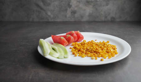 Diet. Organic Grilled Corn, tomato, cucumber on a white plate. Organic farm vegetables. Environmentally friendly productsの写真素材
