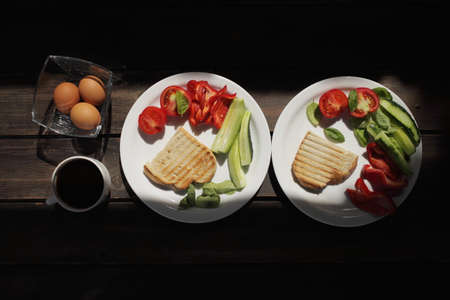 Healthy organic vegetable breakfast, tomato, toast, salad, basil, egg, coffee. Vegetarian healthy food in a white plate on a dark wooden table. High quality photoの写真素材