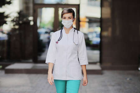 Confident female doctor or nurse wearing a face protective mask. Safety measures against the...