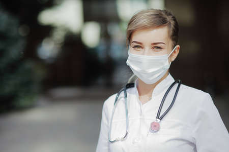Confident female doctor or nurse wearing a face protective mask. Safety measures against the...