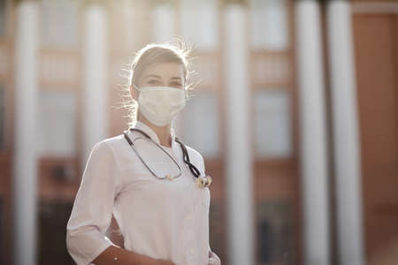 Confident female doctor or nurse wearing a face protective mask. Safety measures against the...