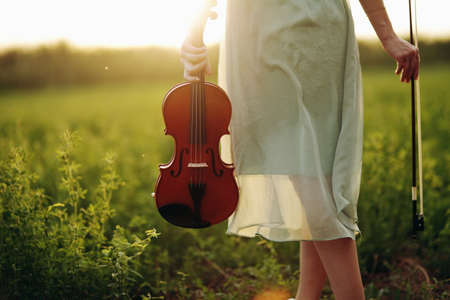 Violin in the hands of a young female violinist in the sunset light. Violin training concept