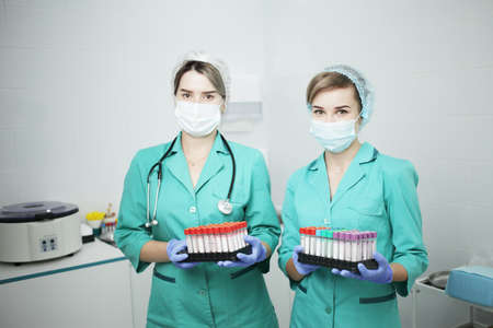 Two female nurses doctor in a hospital in a medical mask and medical clothes hold cones of a test...
