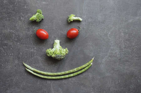 Smiling emoticon of fresh vegetables cherry tomatoes broccoli and green beans. High quality photoの写真素材