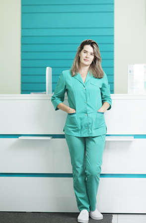 Female doctor or nurse in medical uniform looking at the camera. In the hospital reception.の写真素材