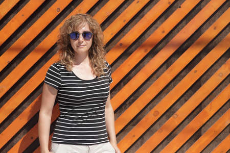 Woman portrait in sunglasses, free space for inscription. Orange wooden wall in the backgroundの写真素材