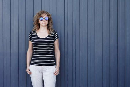 Woman portrait in sunglasses, free space for inscription. Blue striped wall in the backgroundの写真素材