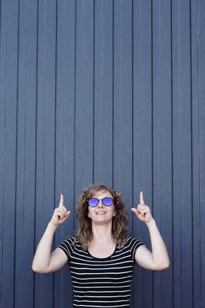 Woman portrait in sunglasses, free space for inscription. Blue striped wall in the backgroundの写真素材