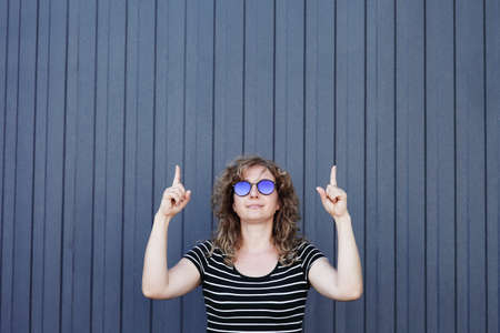 Woman portrait in sunglasses, free space for inscription. Blue striped wall in the background