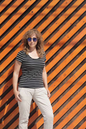 Woman portrait in sunglasses, free space for text. Orange wooden wall in the backgroundの写真素材