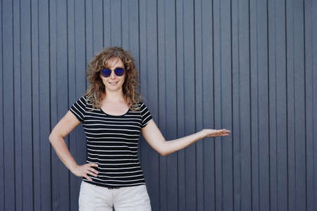 Woman portrait in sunglasses, free space for text. Blue striped wall in the backgroundの写真素材